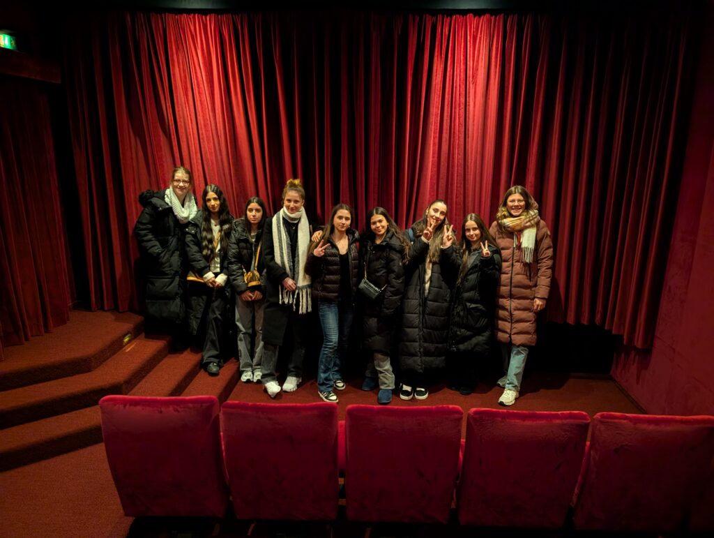Schülerinnengruppe vor einem roten Kinovorhang